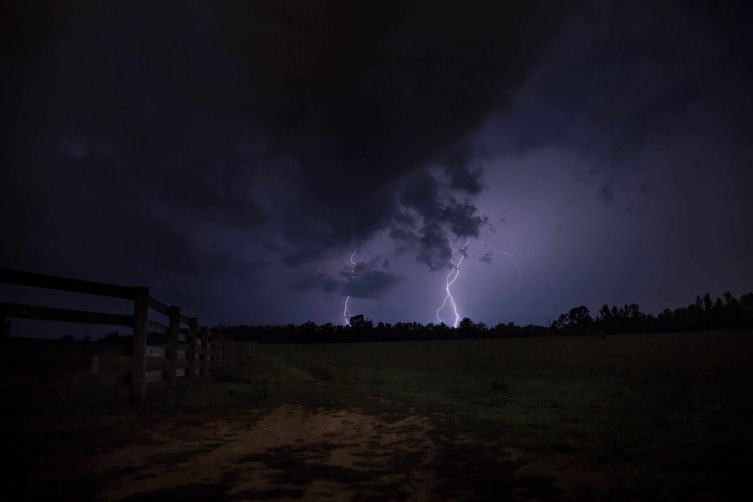 Lightning striking near a dark rural field at night