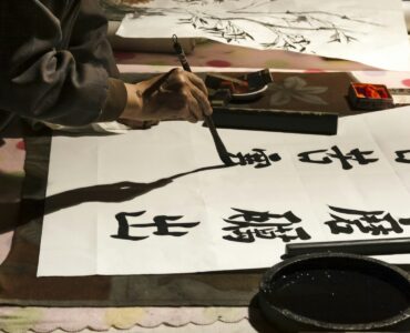 A learner practices Japanese kanji with a calligraphy brush.