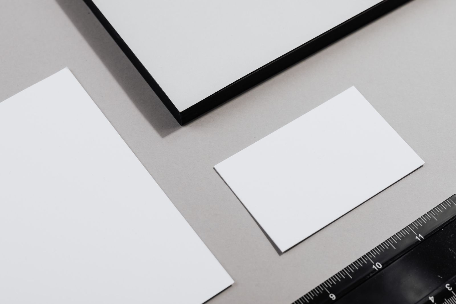 Sheets of white paper arranged beside a ruler on a desk, illustrating standardized paper measurements.