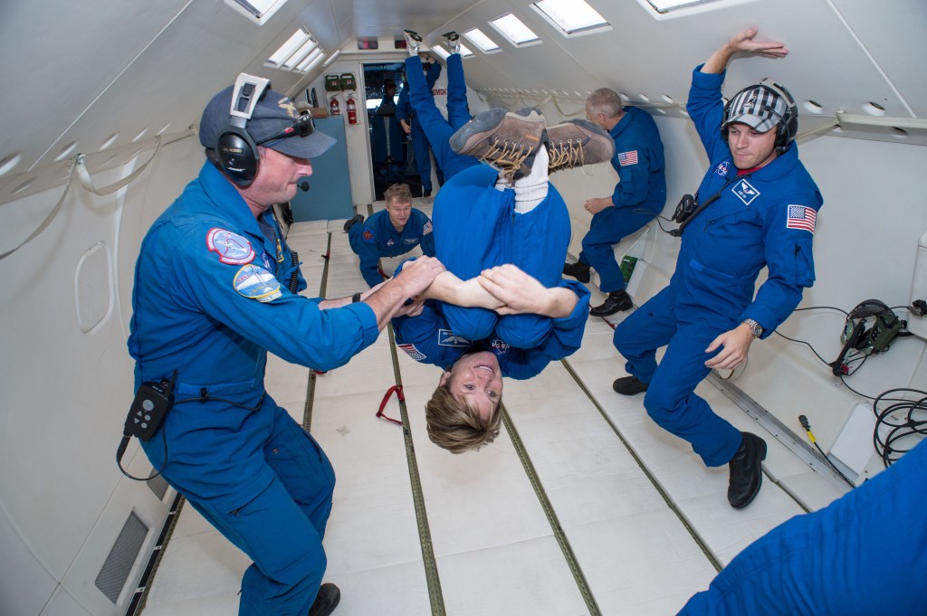 Participants floating inside a NASA C-9 aircraft during a parabolic flight.