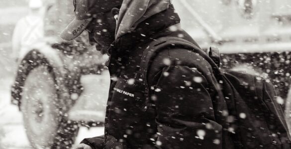 A person checks a smartphone while walking along a snowy city street