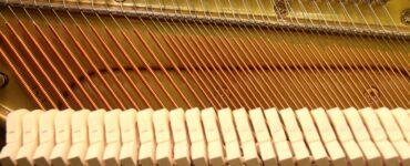 Close view of strings, hammers, and tuning pins inside a piano