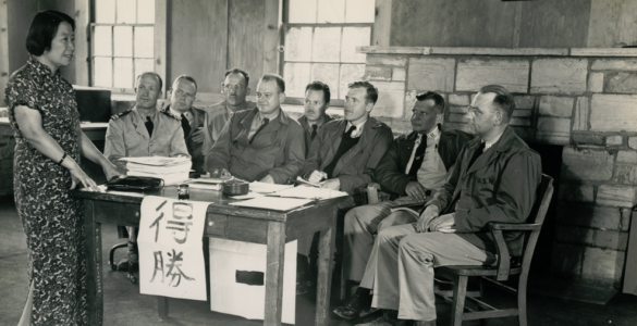 Students learning Mandarin pronunciation with Chinese characters and Pinyin patterns on a classroom board.
