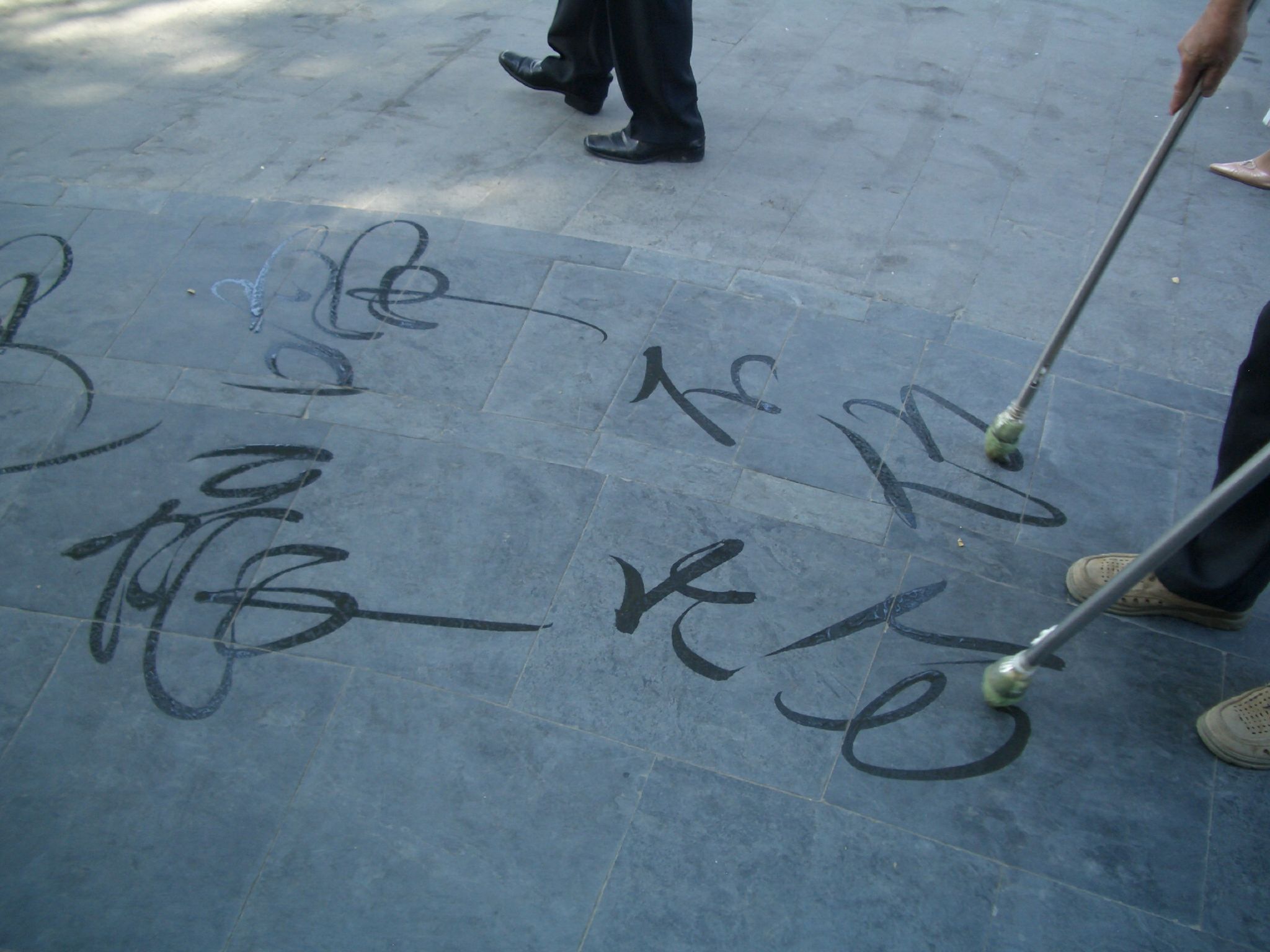 A person practices Chinese characters with a brush after learning the spoken syllables behind them.