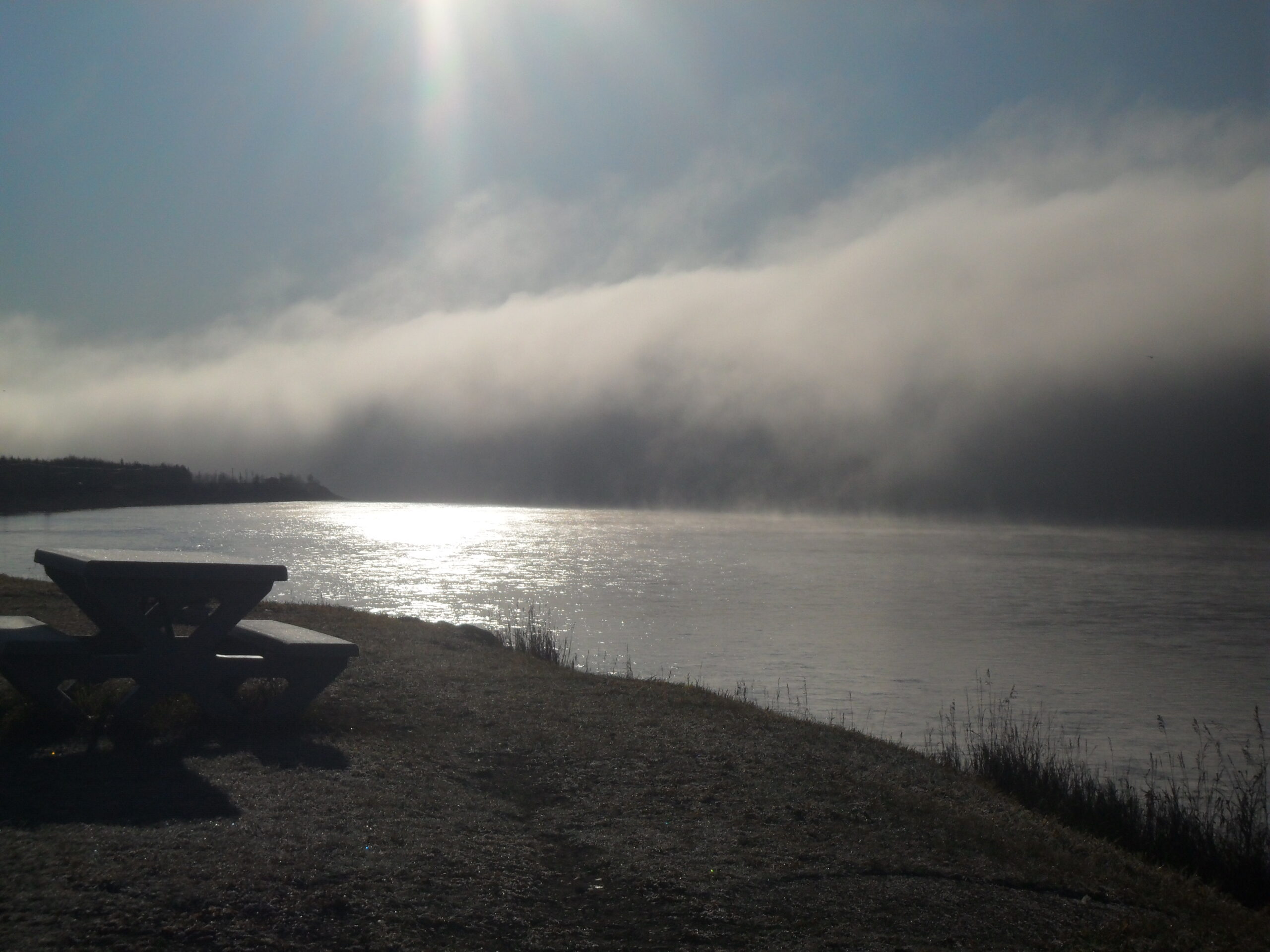 A broad wall of fog hanging above a river valley