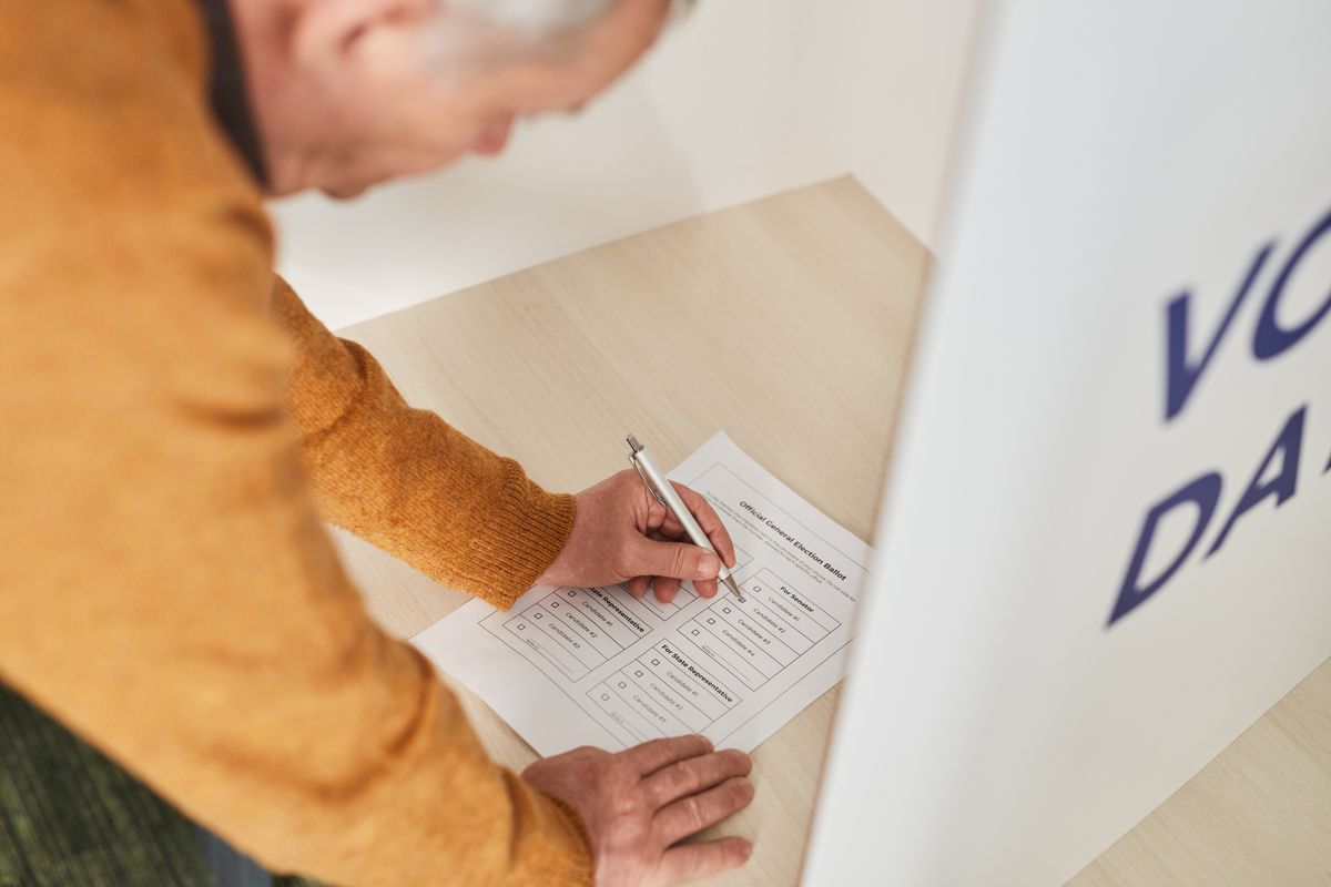 A voter marks a paper ballot at a polling station during an election.