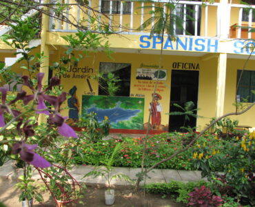 A Spanish language classroom with desks and learning materials for studying adjective placement.