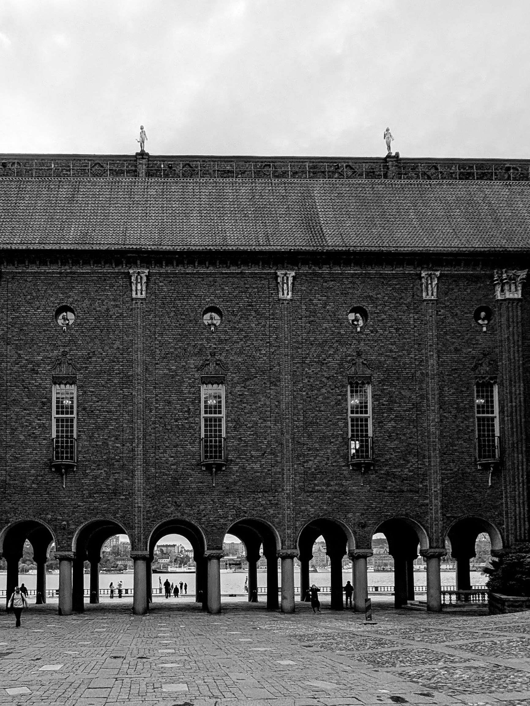 Black-and-white exterior view of Stockholm City Hall with its brick arches.