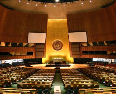 The United Nations General Assembly Hall with rows of delegate desks facing the main rostrum