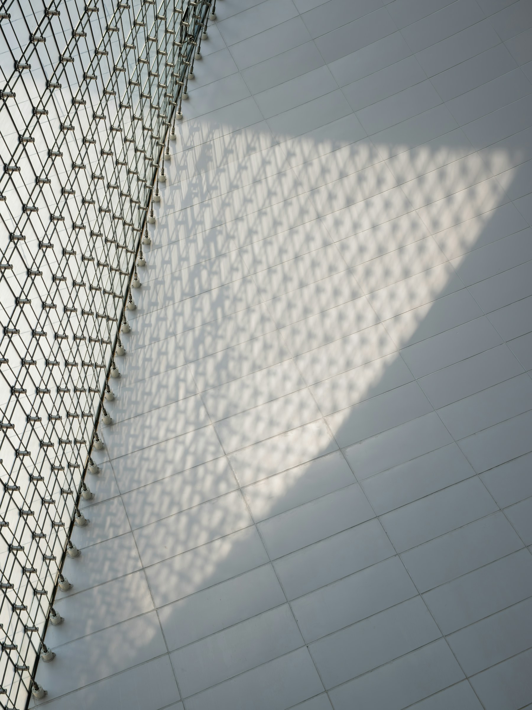 Geometric shadows crossing a tiled architectural surface, showing how light and context shape edges and depth.