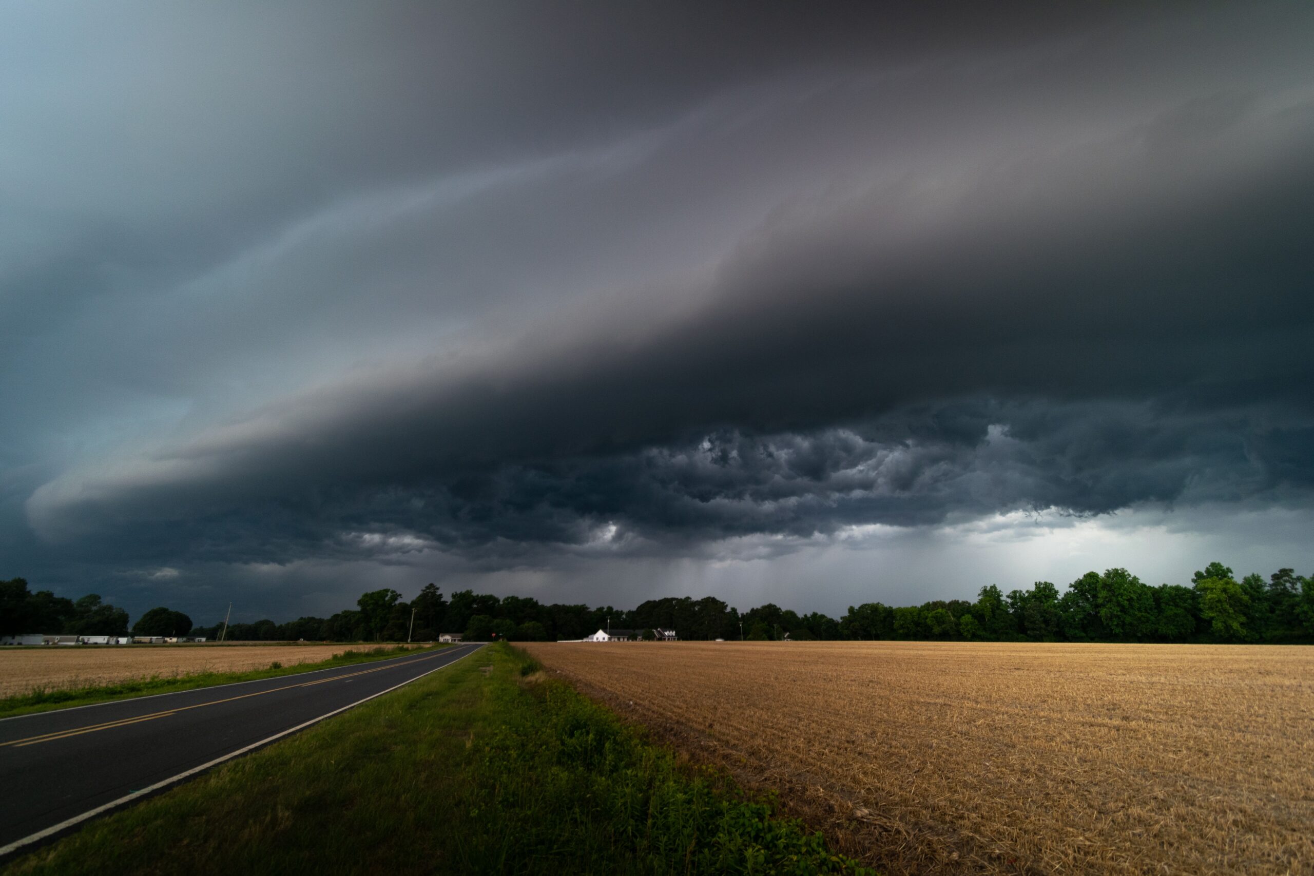 Dark storm clouds over a rural road, showing how storm timing can shift between forecasts.