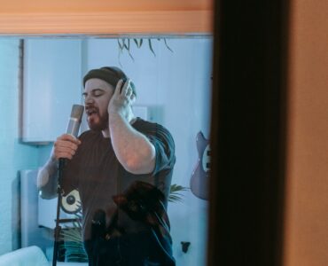 Singer recording beside acoustic wall panels in a professional studio