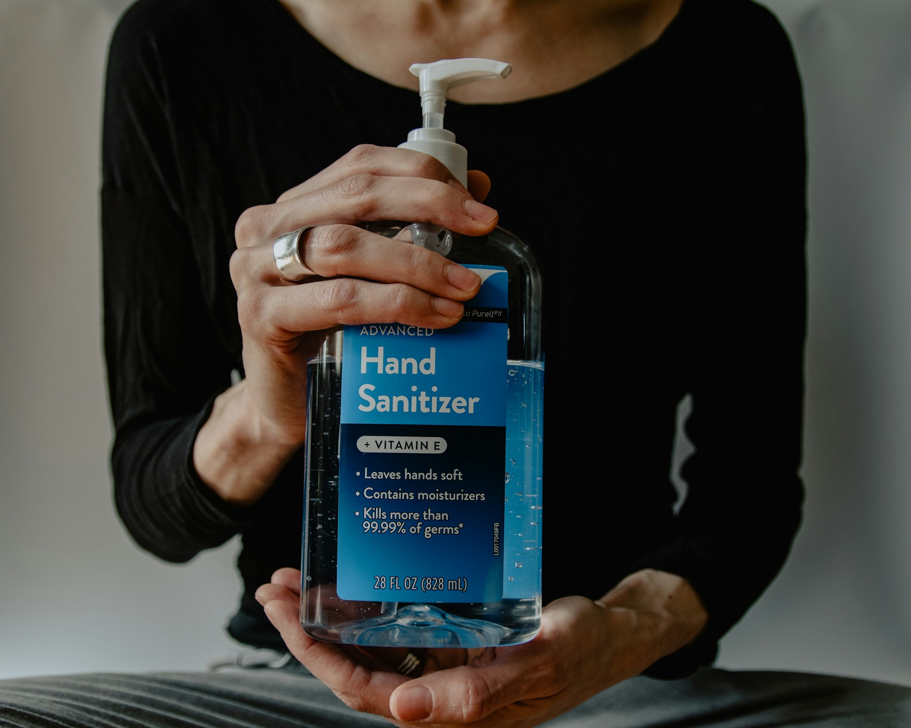 Hands holding a pump bottle of alcohol-based hand sanitizer