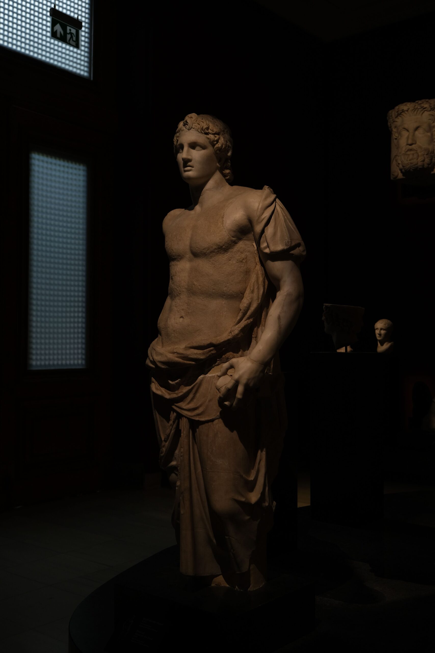 Ancient Greek marble sculpture in dramatic museum lighting