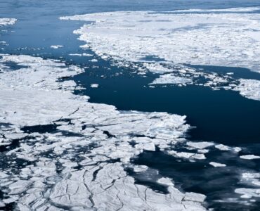 Aerial view of broken sea ice floating across dark polar ocean water