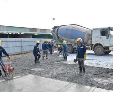 Construction workers guiding wet concrete from a mixer truck