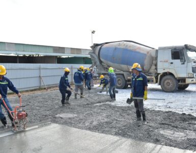 Construction workers guiding wet concrete from a mixer truck