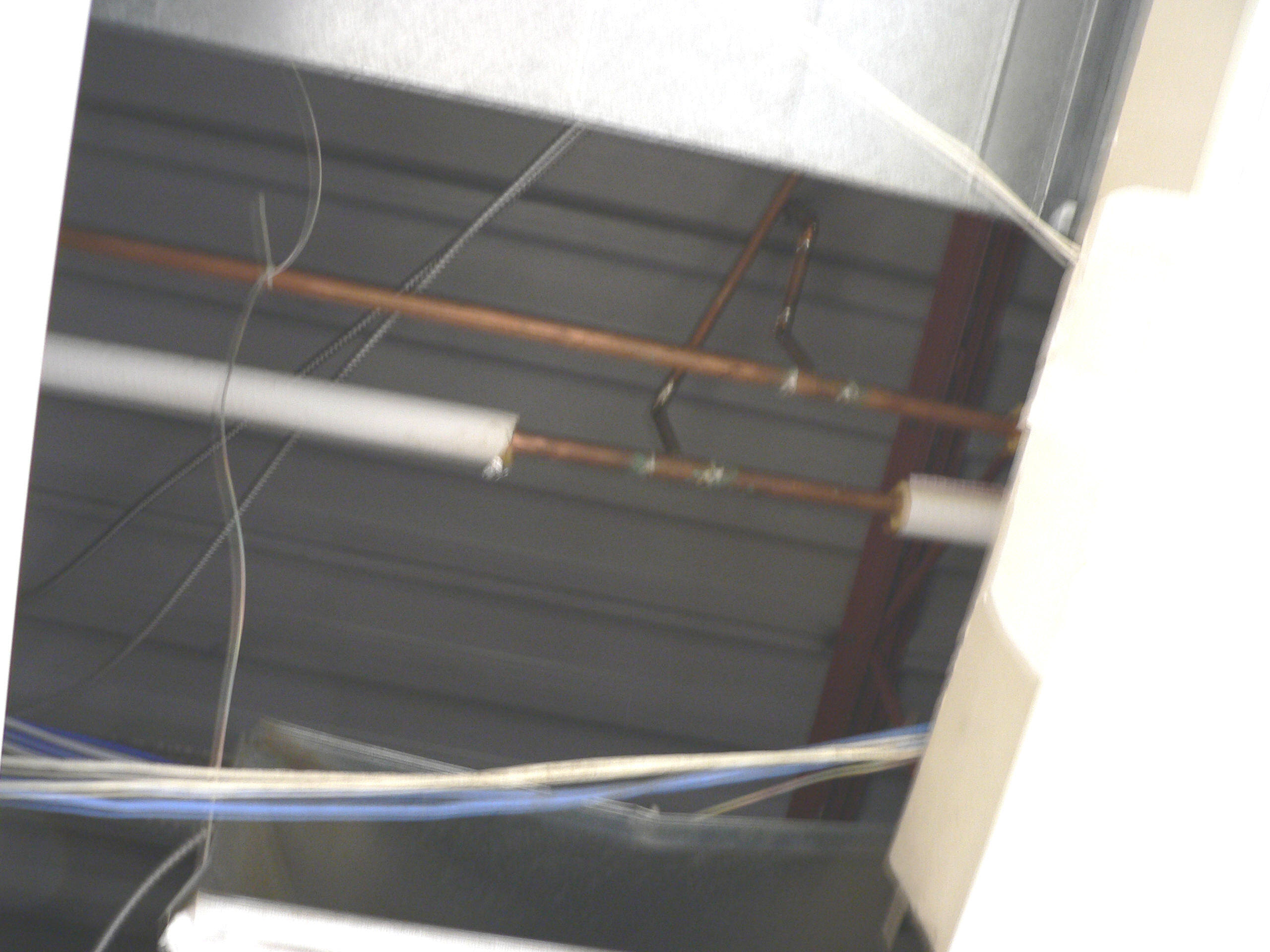 Copper plumbing pipes with and without thermal insulation above a ceiling