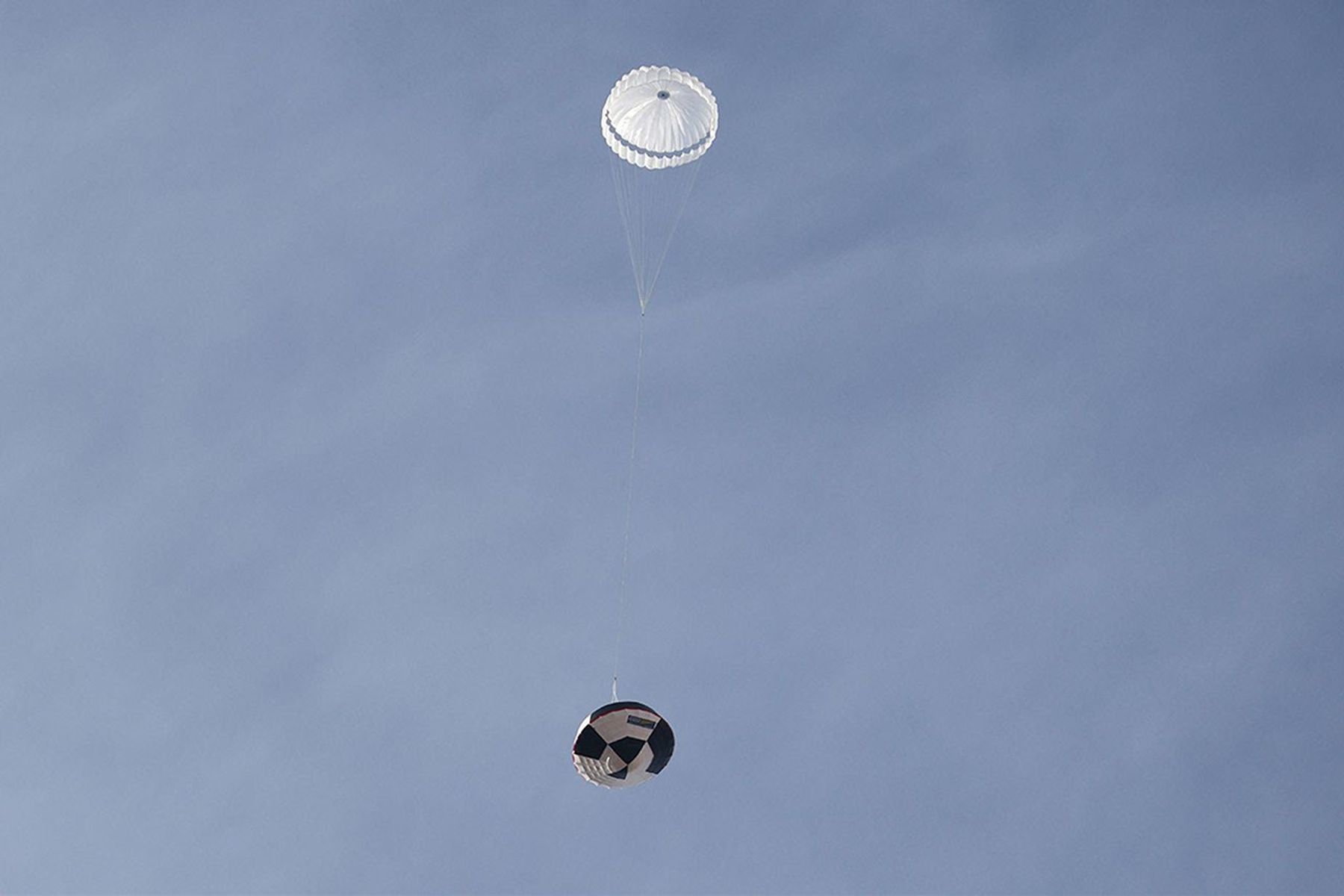 A full-scale Dragonfly parachute lowering a test capsule over the Arizona desert