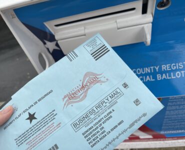 A paper election ballot beside a secure ballot collection box