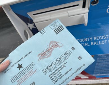 A paper election ballot beside a secure ballot collection box