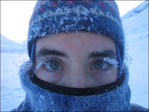 Bundled person with frost on eyelashes in extreme cold