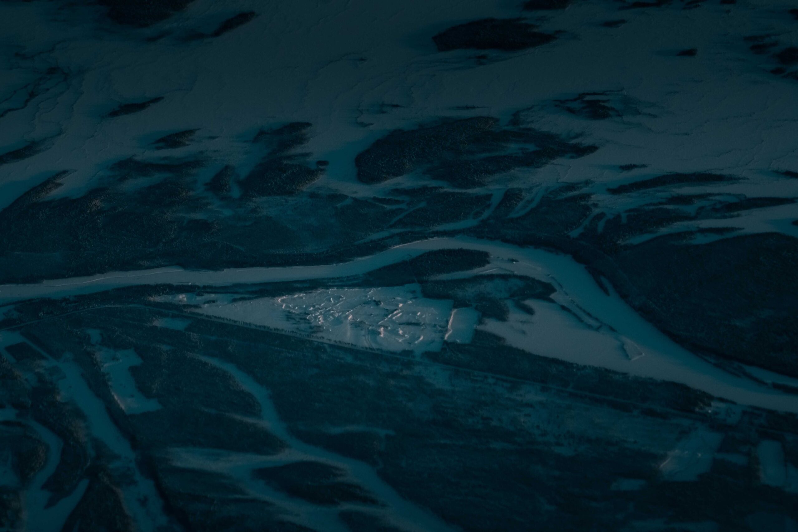 A frozen river winding through a snow-covered northern valley