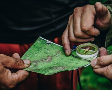 Two people use a paper map and compass while standing outdoors