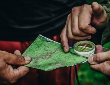 Two people use a paper map and compass while standing outdoors