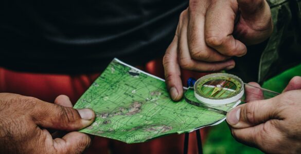 Two people use a paper map and compass while standing outdoors