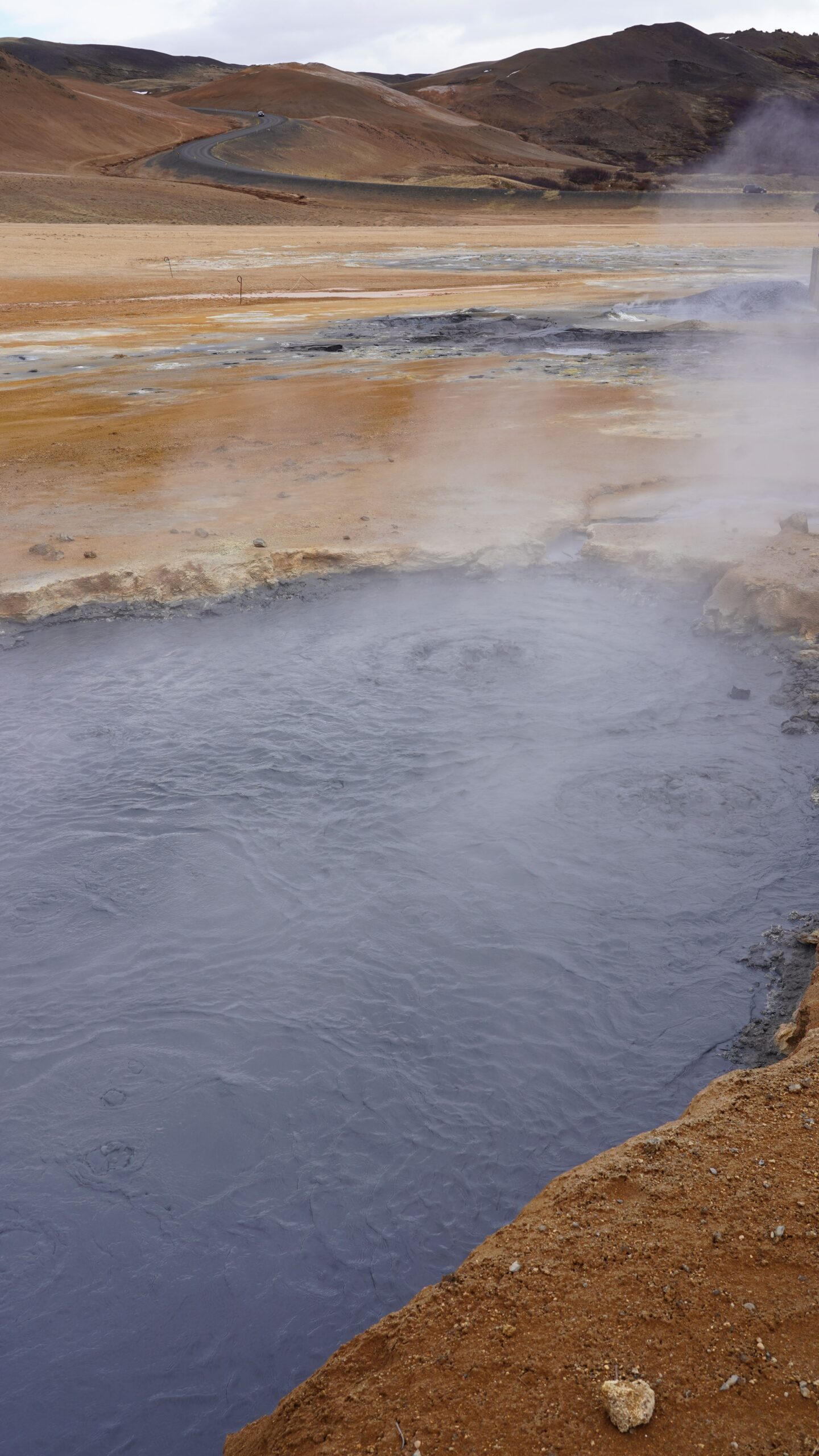 Steam rising from a geothermal pool in a rocky landscape