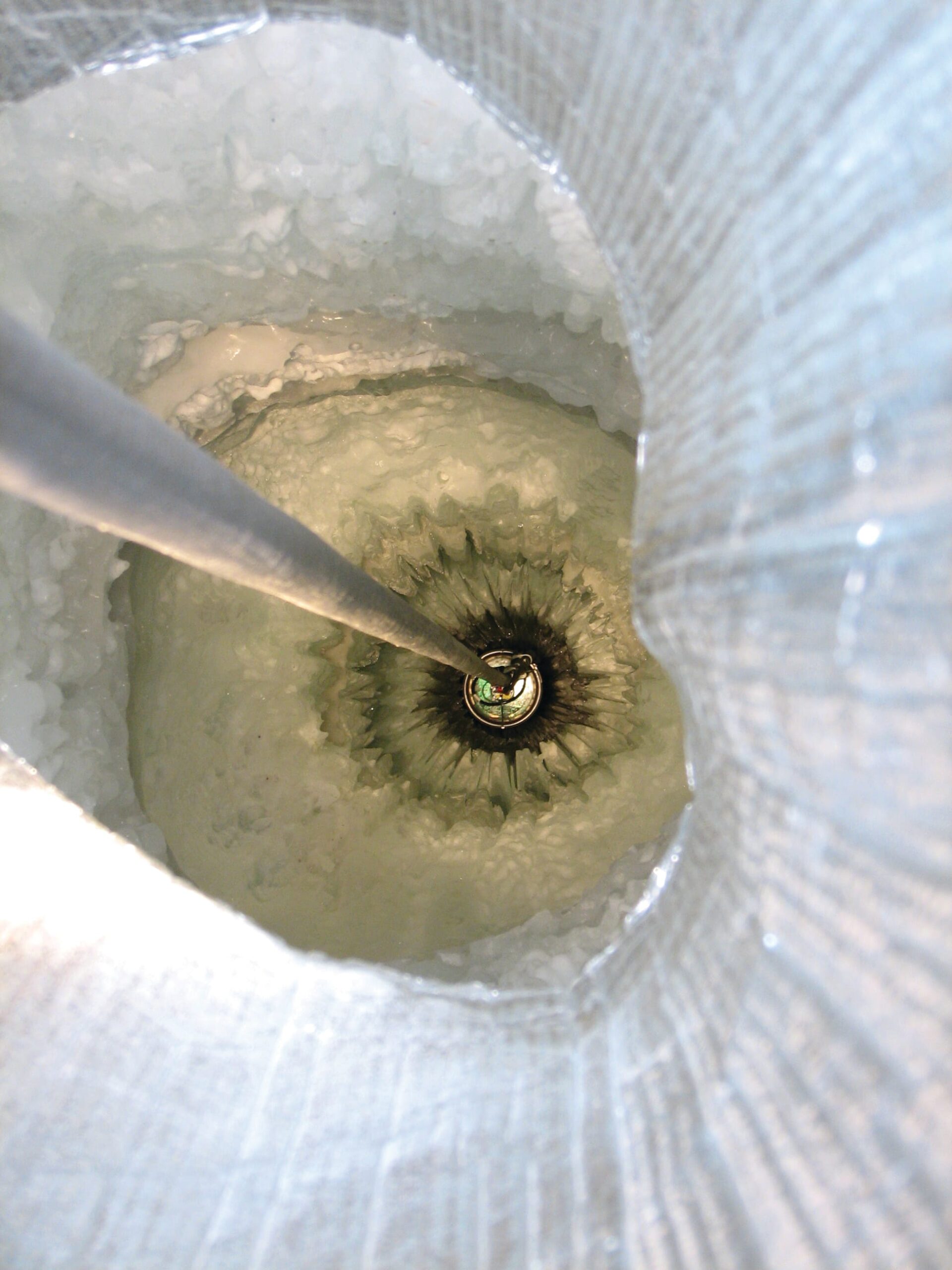 An IceCube digital optical module being lowered into a drilled hole in Antarctic ice.