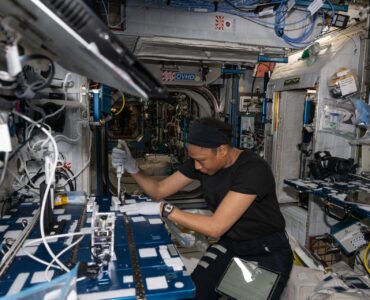 NASA astronaut Jeanette Epps uses a pipette to analyze bacteria samples aboard the International Space Station
