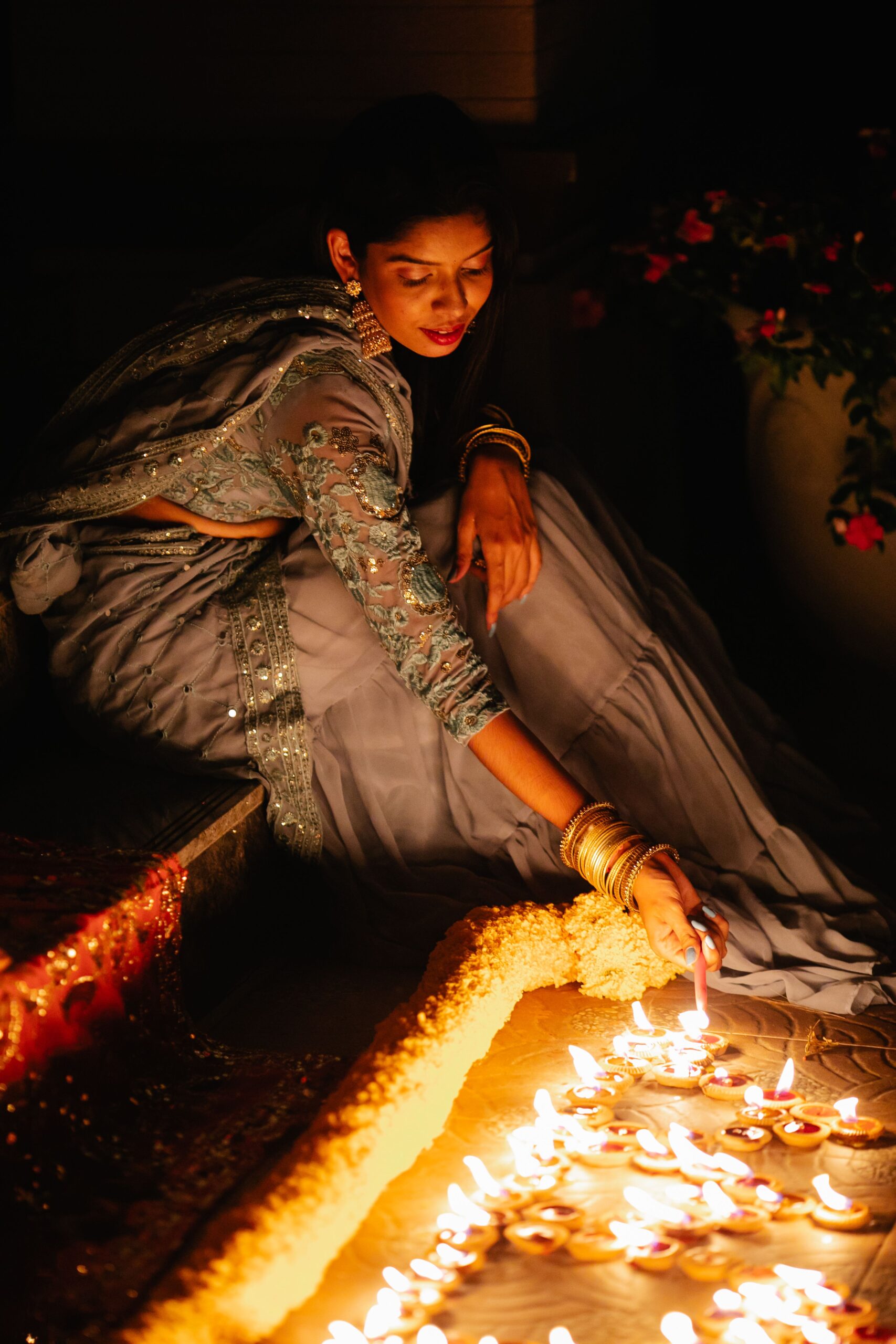 A woman in traditional attire lighting diyas for Diwali
