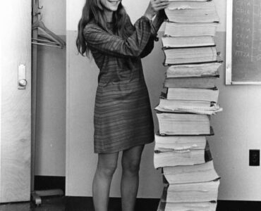 Margaret Hamilton standing beside printed listings of the Apollo flight software