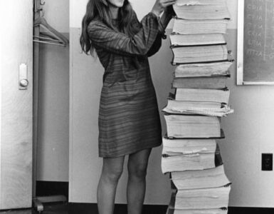 Margaret Hamilton standing beside printed listings of the Apollo flight software