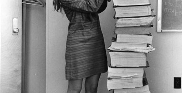 Margaret Hamilton standing beside printed listings of the Apollo flight software