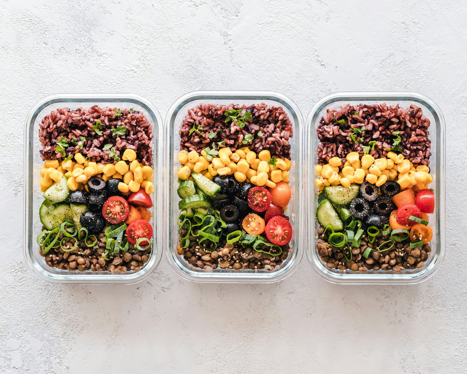 Prepared meals in glass containers with vegetables, rice, and lentils