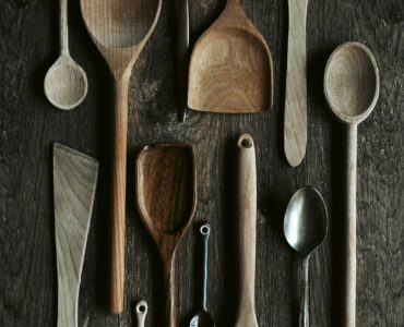 Metal and wooden spoons arranged together on a dark surface