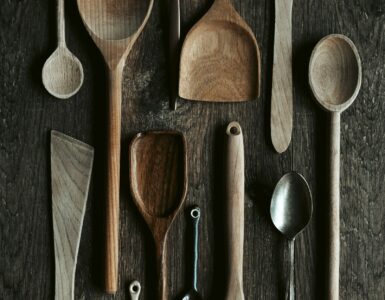 Metal and wooden spoons arranged together on a dark surface