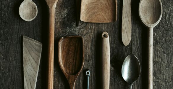 Metal and wooden spoons arranged together on a dark surface