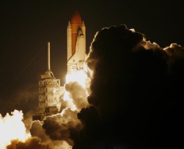 Rocket lifting off at night through a cloud of exhaust