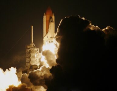 Rocket lifting off at night through a cloud of exhaust