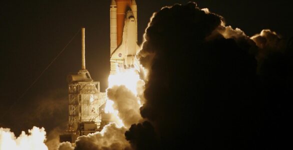 Rocket lifting off at night through a cloud of exhaust