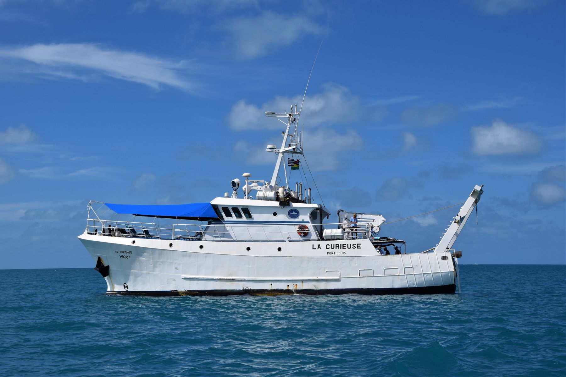 White oceanographic research vessel traveling across open blue water