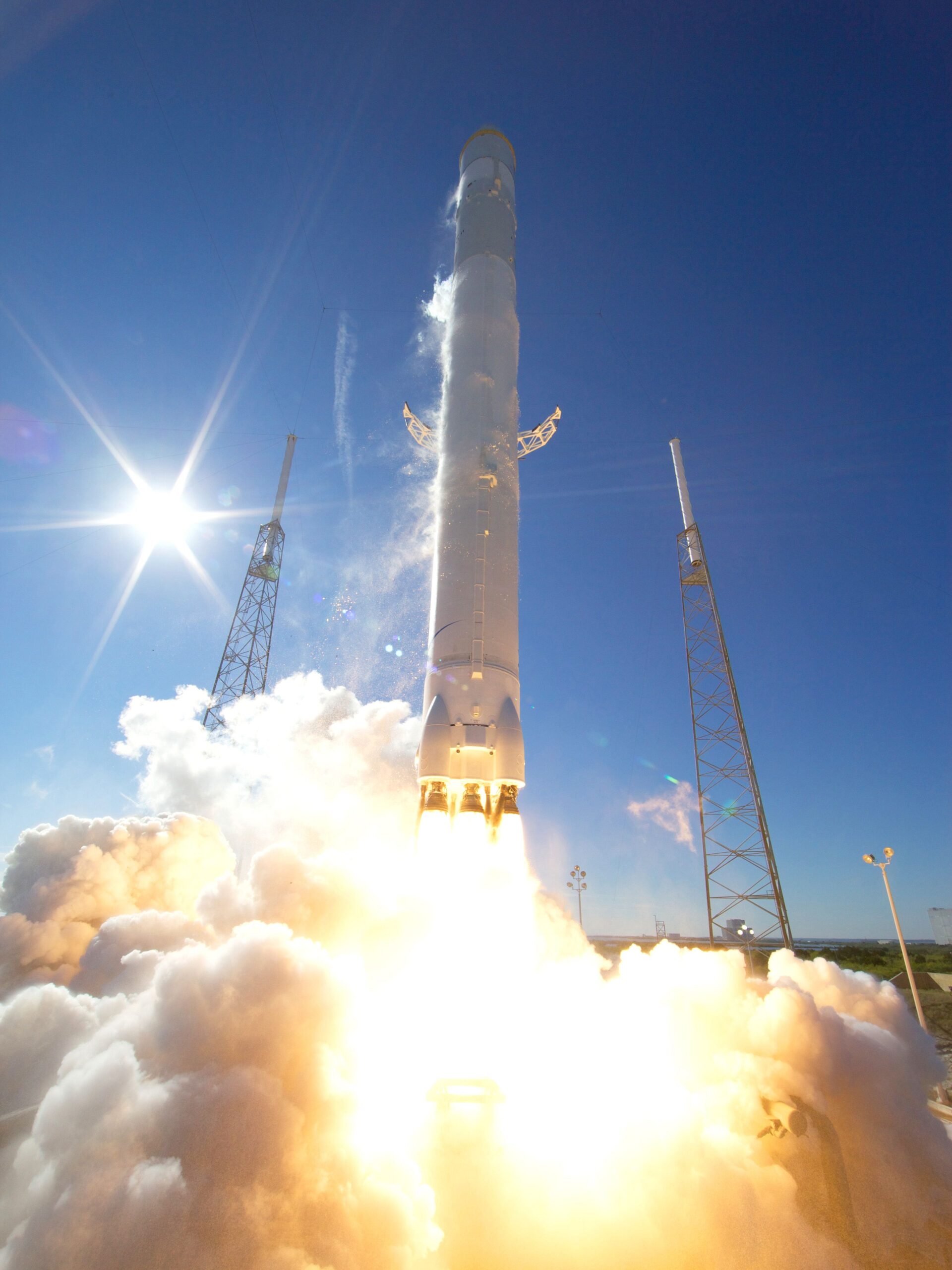 Rocket climbing through a blue sky above a bright exhaust plume
