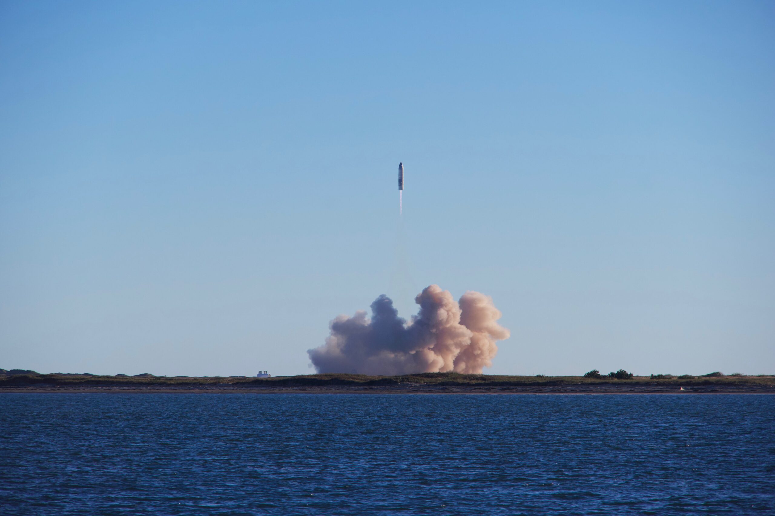 A rocket rising above the ocean with a bright exhaust trail