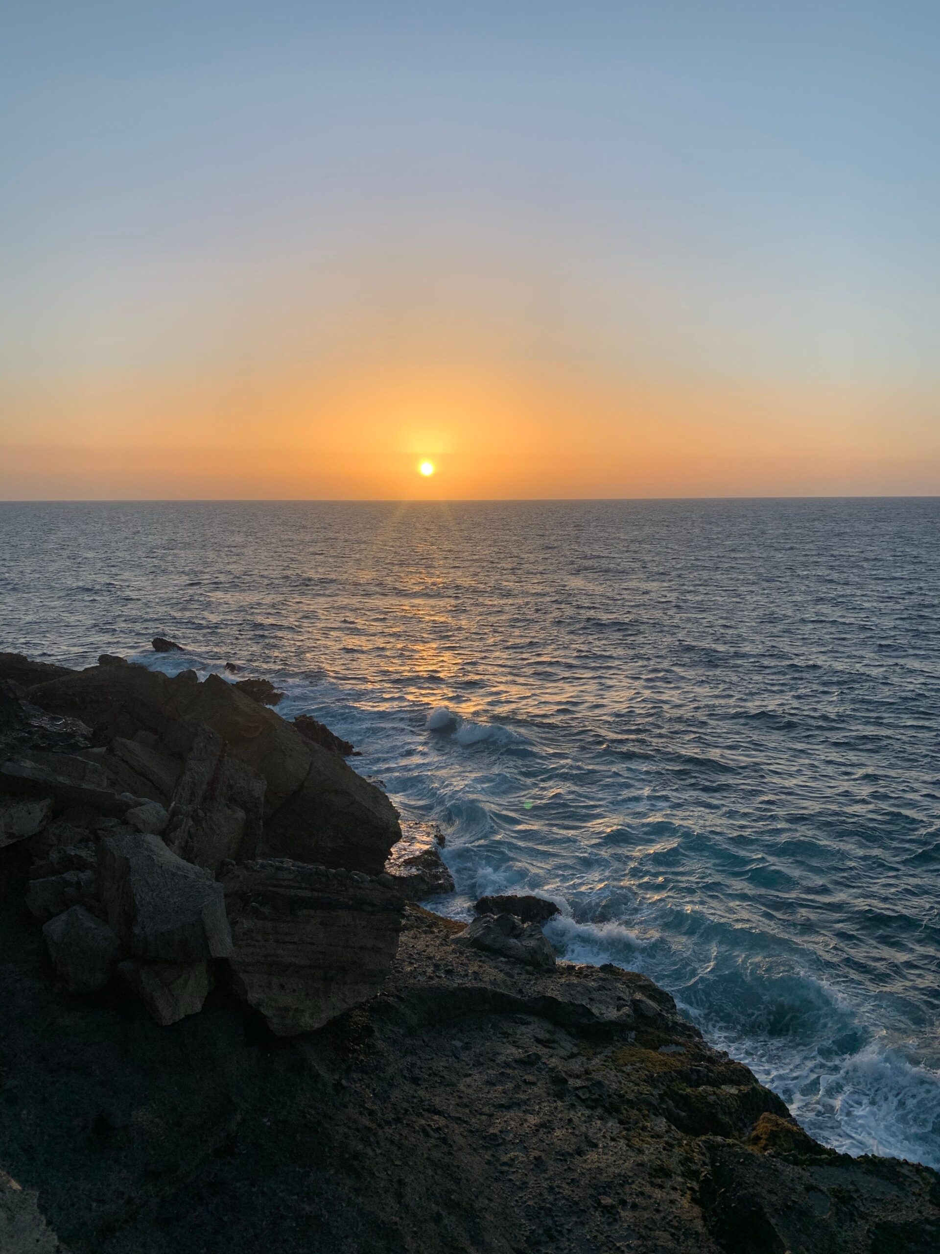 Ocean waves beside a rocky coast at dusk