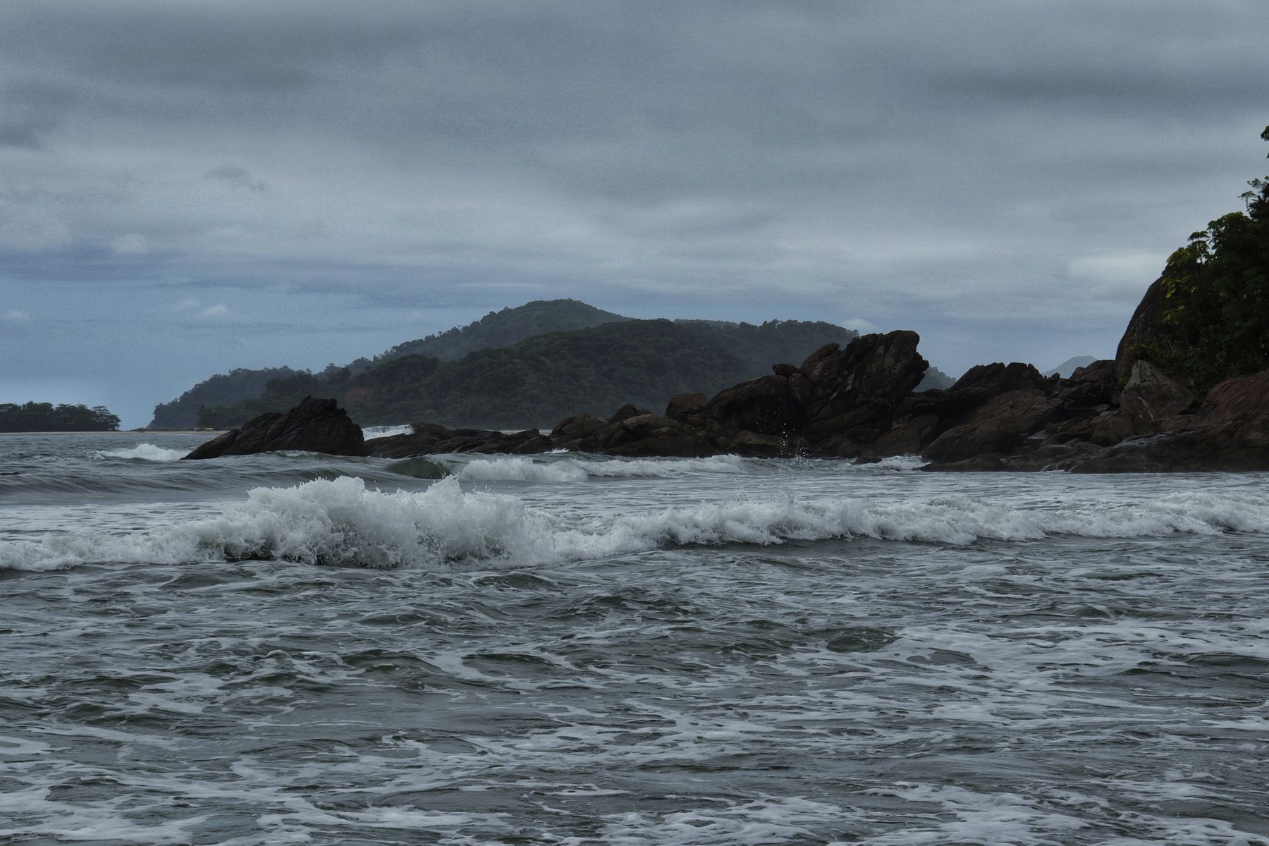 Powerful ocean waves rolling beneath an overcast sky