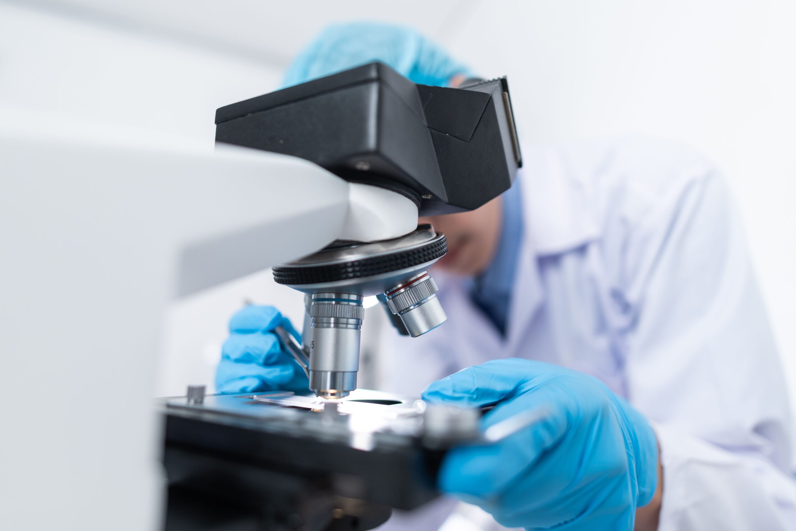 A scientist examining a sample through a microscope in a laboratory